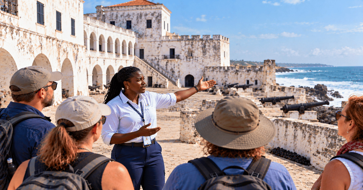 Guide touristique présentant une ancienne forteresse côtière en pierre à un groupe de visiteurs face à l’océan.